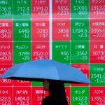 A woman walks past an electronic board showing the Nikkei 225 index on the Tokyo Stock Exchange in Tokyo on June 17, 2025. (Photo by Kazuhiro NOGI / AFP)